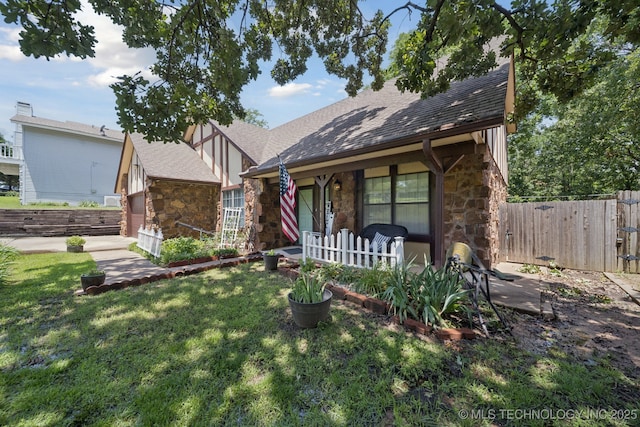 2519 W 53rd St, Tulsa, OK 74107 - tudor home featuring stone siding, covered porch, roof with shingles, and an outdoor structure