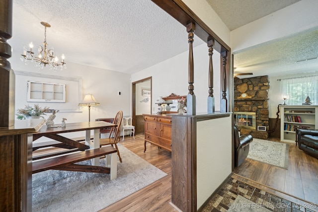 2519 W 53rd St, Tulsa, OK 74107 - dining room with a textured ceiling, a chandelier, a stone fireplace, wood finished floors, and a ceiling fan