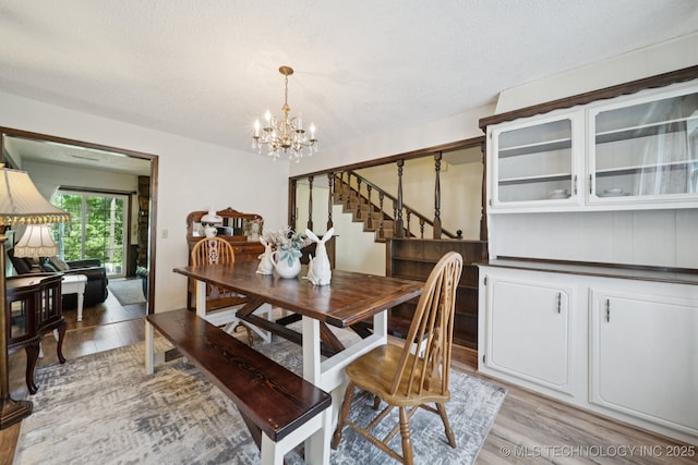 2519 W 53rd St, Tulsa, OK 74107 - dining room featuring light wood-style flooring, a chandelier, stairway, and a textured ceiling