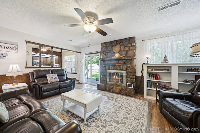 2519 W 53rd St, Tulsa, OK 74107 - living area featuring a ceiling fan, a textured ceiling, wood finished floors, and a stone fireplace