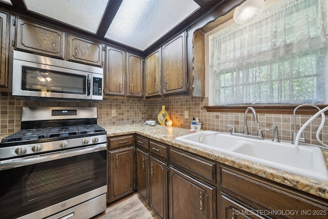 2519 W 53rd St, Tulsa, OK 74107 - kitchen with appliances with stainless steel finishes, backsplash, light countertops, dark brown cabinets, and light wood-type flooring