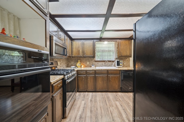 2519 W 53rd St, Tulsa, OK 74107 - kitchen with black appliances, tasteful backsplash, light wood-type flooring, and light stone counters