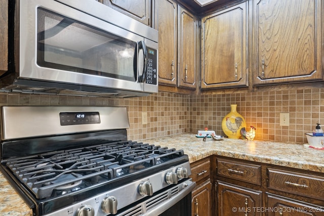 2519 W 53rd St, Tulsa, OK 74107 - kitchen featuring stainless steel appliances, decorative backsplash, and light stone countertops
