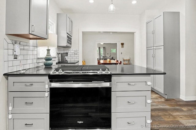 1144 S Owasso Ave, Tulsa, OK 74120 - kitchen featuring stainless steel gas range, dark wood-style flooring, dark countertops, backsplash, and recessed lighting