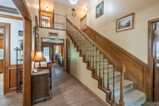 5833 E 78th Pl, Tulsa, OK 74136 - stairway featuring wood finished floors, a wainscoted wall, and a high ceiling