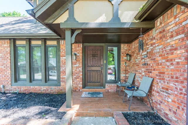 5833 E 78th Pl, Tulsa, OK 74136 - property entrance featuring brick siding, covered porch, and a shingled roof
