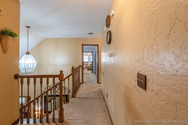5833 E 78th Pl, Tulsa, OK 74136 - hallway featuring light carpet, an upstairs landing, a textured wall, a chandelier, and vaulted ceiling