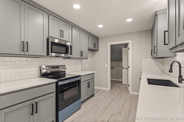 9421 S 69th E Ave, Tulsa, OK 74133 - kitchen featuring appliances with stainless steel finishes, gray cabinetry, light wood-style flooring, decorative backsplash, and recessed lighting