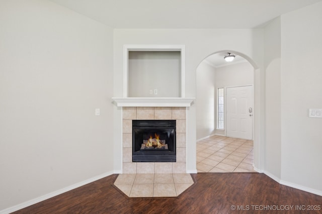 2109 W Maple St, Collinsville, OK 74021 - unfurnished living room featuring arched walkways, wood finished floors, and a tiled fireplace