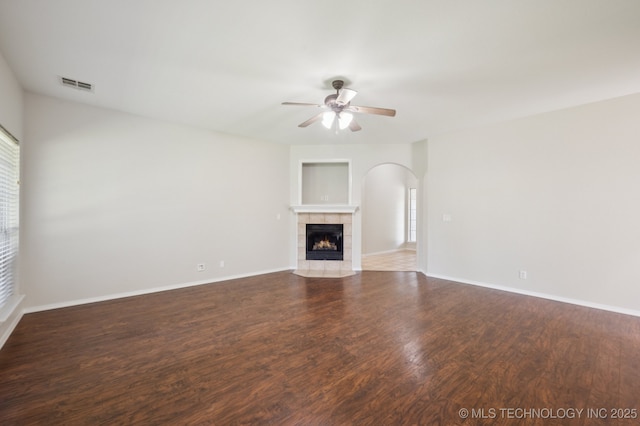 2109 W Maple St, Collinsville, OK 74021 - unfurnished living room featuring ceiling fan, dark wood finished floors, a fireplace, and arched walkways