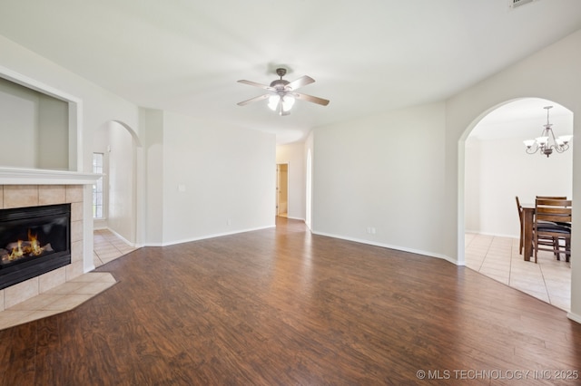 2109 W Maple St, Collinsville, OK 74021 - unfurnished living room with arched walkways, wood finished floors, a tiled fireplace, and a ceiling fan