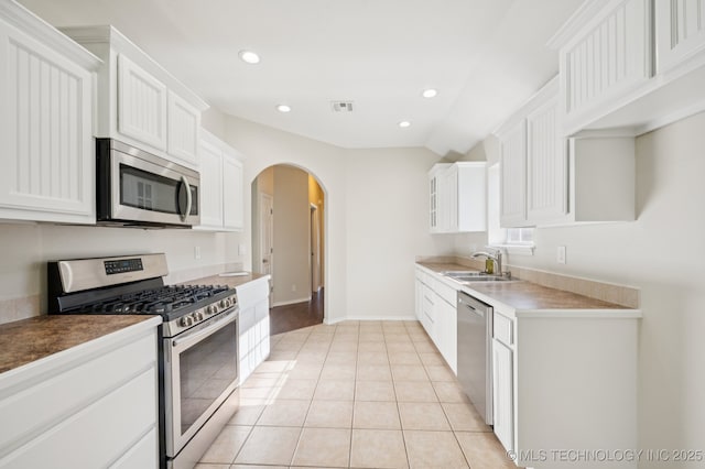 2109 W Maple St, Collinsville, OK 74021 - kitchen with stainless steel appliances, arched walkways, white cabinetry, recessed lighting, and light tile patterned floors
