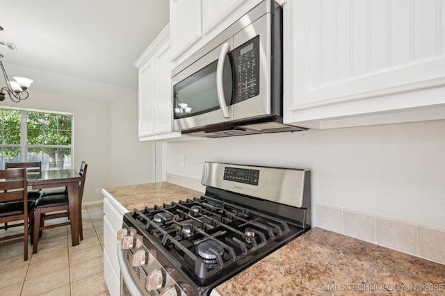 2109 W Maple St, Collinsville, OK 74021 - kitchen featuring stainless steel appliances, a chandelier, white cabinets, light tile patterned flooring, and decorative light fixtures