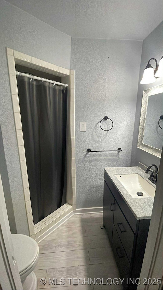219 N Anthony St, Muskogee, OK 74403 - bathroom featuring a textured wall, vanity, wood finished floors, and a shower stall