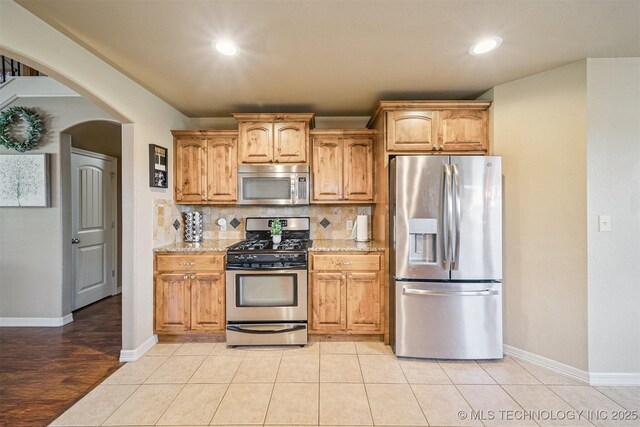 13037 N 124th E Pl, Collinsville, OK 74021 - kitchen featuring stainless steel appliances, arched walkways, tasteful backsplash, light stone counters, and recessed lighting