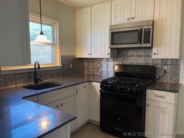 5003 S Boston Ave, Tulsa, OK 74105 - kitchen with stainless steel microwave, black gas stove, white cabinetry, and backsplash