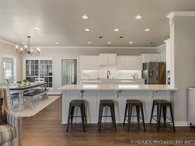 408 W Fairway Ct, Broken Arrow, OK 74011 - kitchen with stainless steel fridge, ornamental molding, a chandelier, white cabinets, and tasteful backsplash