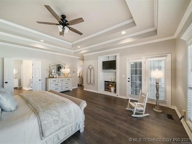408 W Fairway Ct, Broken Arrow, OK 74011 - bedroom with a tray ceiling, crown molding, a lit fireplace, dark wood-type flooring, and recessed lighting