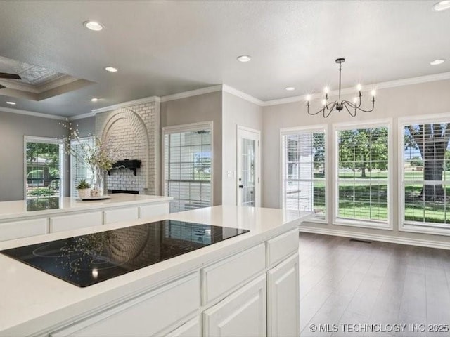 408 W Fairway Ct, Broken Arrow, OK 74011 - kitchen featuring black electric cooktop, a chandelier, healthy amount of natural light, ornamental molding, and white cabinets