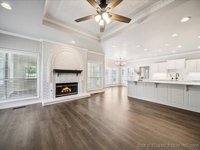 408 W Fairway Ct, Broken Arrow, OK 74011 - unfurnished living room featuring a tray ceiling, a chandelier, crown molding, a fireplace, and a ceiling fan