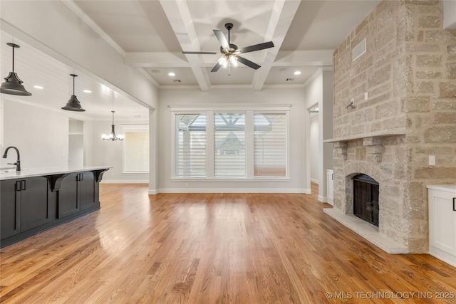 5913 E 127th St S, Tulsa, OK 74008 - unfurnished living room with coffered ceiling, a ceiling fan, a fireplace, light wood-style flooring, and a chandelier
