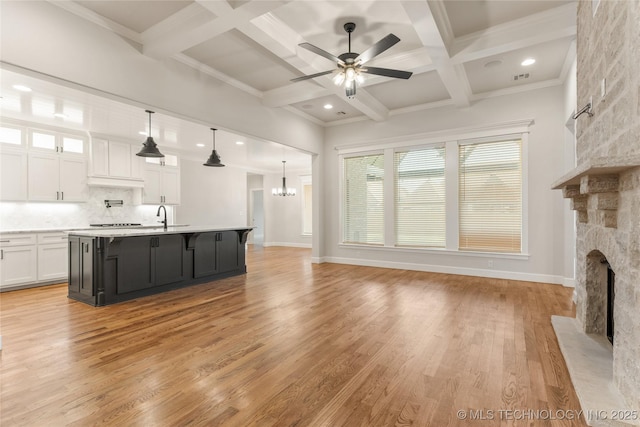 5913 E 127th St S, Tulsa, OK 74008 - unfurnished living room featuring a fireplace, ceiling fan, beam ceiling, coffered ceiling, and light wood finished floors