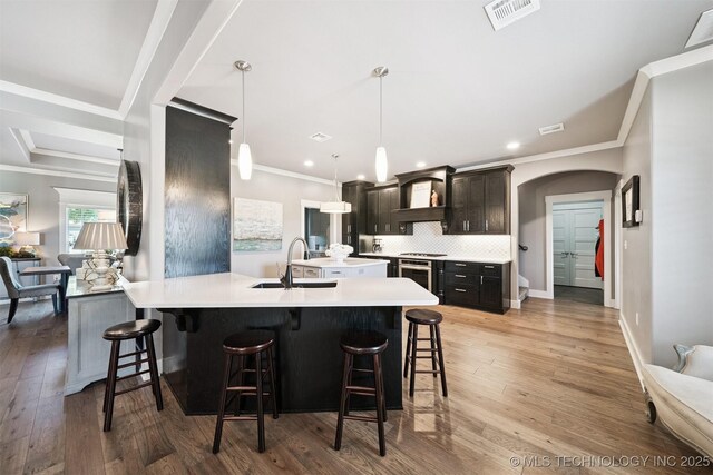 27920 160th St, Coweta, OK 74429 - kitchen featuring a kitchen breakfast bar, light countertops, ornamental molding, decorative backsplash, and light wood-style flooring