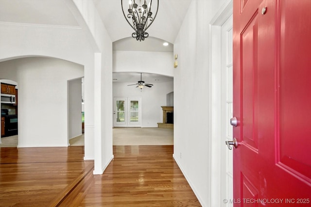 1005 E Fargo St, Broken Arrow, OK 74012 - entrance foyer featuring arched walkways, a ceiling fan, light wood-style flooring, a fireplace with raised hearth, and a chandelier