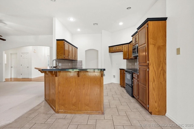 1005 E Fargo St, Broken Arrow, OK 74012 - kitchen featuring black / electric stove, stainless steel microwave, a peninsula, dark countertops, and arched walkways