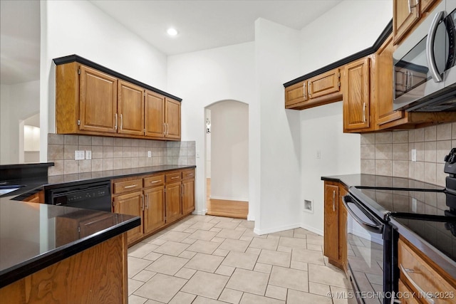 1005 E Fargo St, Broken Arrow, OK 74012 - kitchen with black appliances, dark countertops, arched walkways, brown cabinetry, and recessed lighting