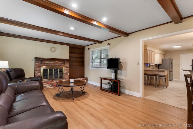 6016 E 52nd Pl, Tulsa, OK 74135 - living room with beam ceiling, light wood-style flooring, a brick fireplace, and ornamental molding