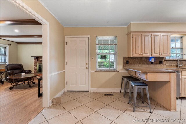 6016 E 52nd Pl, Tulsa, OK 74135 - kitchen with plenty of natural light, light brown cabinets, a breakfast bar, and crown molding