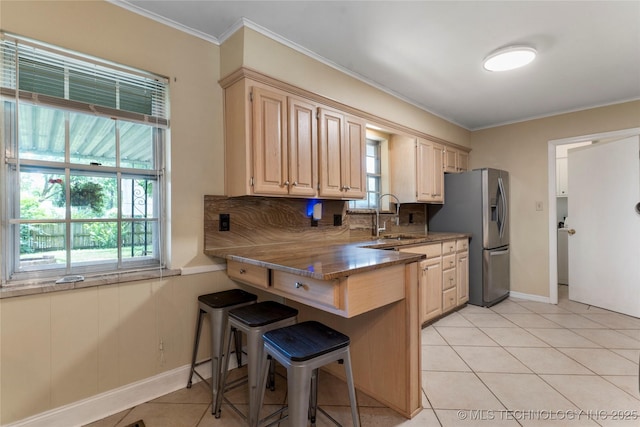 6016 E 52nd Pl, Tulsa, OK 74135 - kitchen featuring stainless steel fridge, a breakfast bar, light tile patterned floors, light stone countertops, and ornamental molding