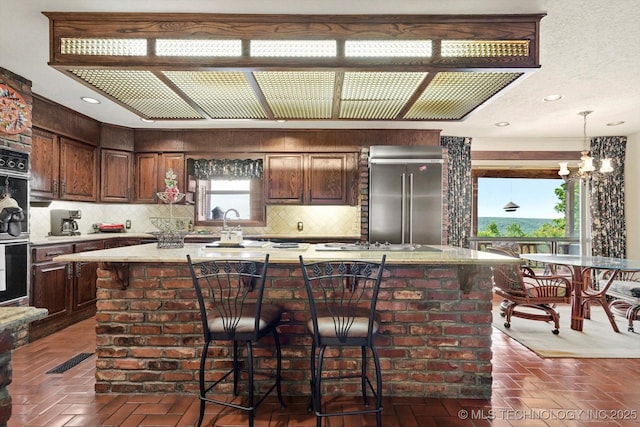 17331 S 174th Ave E, Bixby, OK 74008 - kitchen with high end fridge, backsplash, light countertops, and a chandelier