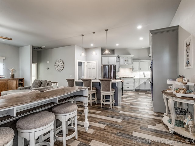 353800 E 5400th Rd, Maramec Twp, OK 74045 - kitchen featuring freestanding refrigerator, a breakfast bar, decorative backsplash, open floor plan, and dark wood-style floors