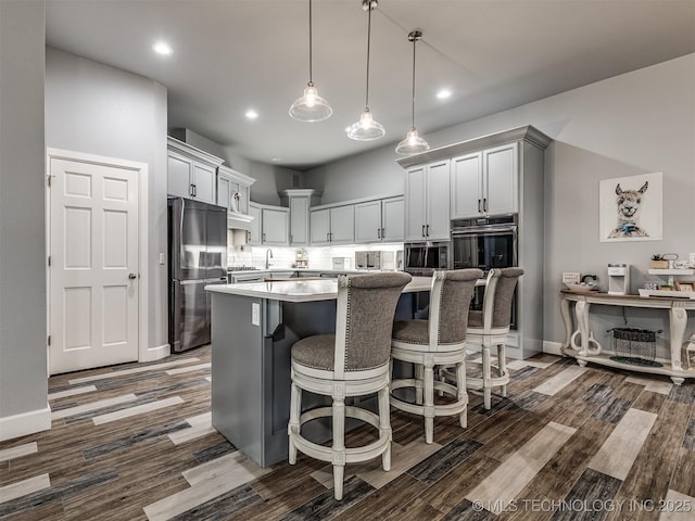 353800 E 5400th Rd, Maramec Twp, OK 74045 - kitchen featuring appliances with stainless steel finishes, dark wood-style flooring, a kitchen bar, light countertops, and a kitchen island