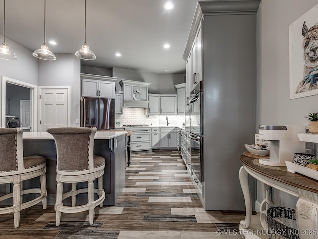 353800 E 5400th Rd, Maramec Twp, OK 74045 - kitchen with stainless steel fridge, washer / clothes dryer, a breakfast bar area, backsplash, and dark wood finished floors