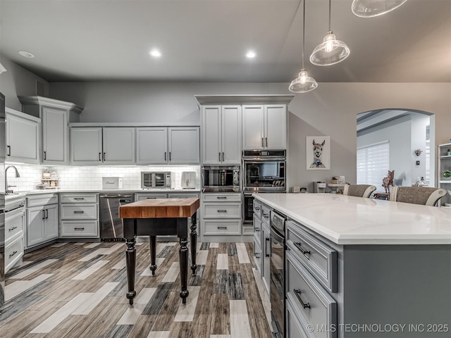353800 E 5400th Rd, Maramec Twp, OK 74045 - kitchen featuring appliances with stainless steel finishes, arched walkways, gray cabinets, decorative light fixtures, and decorative backsplash