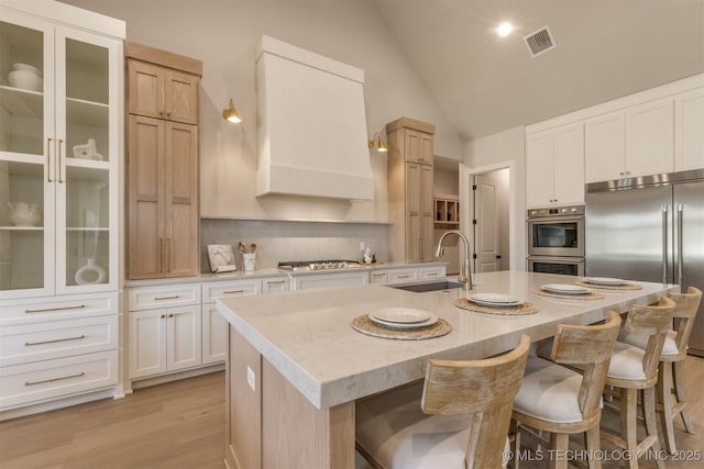 3528 S Troost Ave, Tulsa, OK 74105 - kitchen with appliances with stainless steel finishes, light countertops, a breakfast bar area, a center island with sink, and light wood-style floors