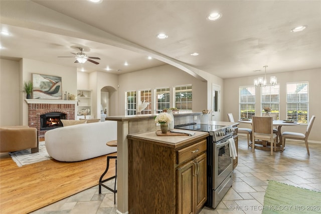 11936 S 98th E Ave, Bixby, OK 74008 - kitchen with stainless steel electric range, stone tile flooring, a brick fireplace, recessed lighting, and a ceiling fan