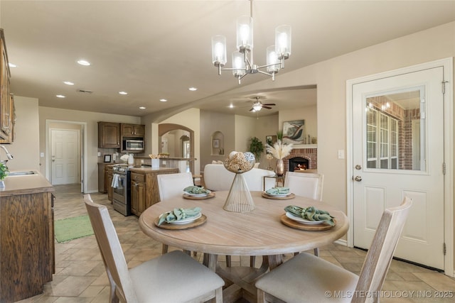 11936 S 98th E Ave, Bixby, OK 74008 - dining area featuring arched walkways, ceiling fan, a brick fireplace, recessed lighting, and a chandelier