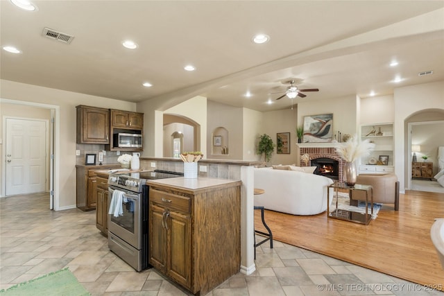 11936 S 98th E Ave, Bixby, OK 74008 - kitchen featuring appliances with stainless steel finishes, a breakfast bar, arched walkways, a ceiling fan, and recessed lighting