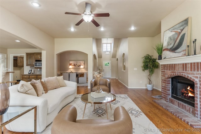 11936 S 98th E Ave, Bixby, OK 74008 - living area featuring ceiling fan, a brick fireplace, light wood-style floors, recessed lighting, and arched walkways