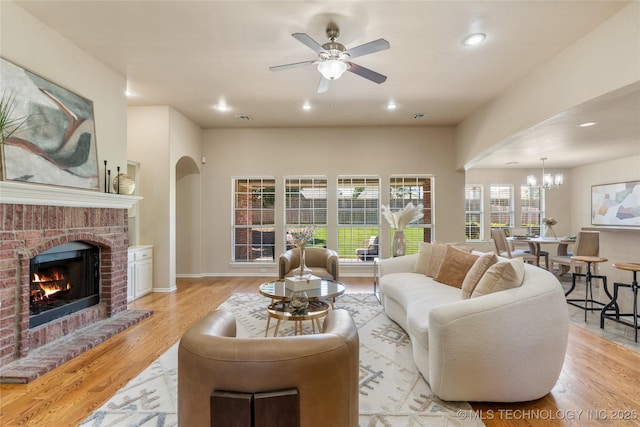 11936 S 98th E Ave, Bixby, OK 74008 - living area featuring a ceiling fan, light wood-type flooring, a fireplace, arched walkways, and a chandelier
