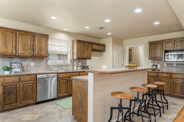 11936 S 98th E Ave, Bixby, OK 74008 - kitchen featuring appliances with stainless steel finishes, backsplash, a breakfast bar area, recessed lighting, and a kitchen island