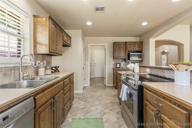 11936 S 98th E Ave, Bixby, OK 74008 - kitchen featuring stainless steel appliances, tasteful backsplash, light stone finish floors, arched walkways, and recessed lighting
