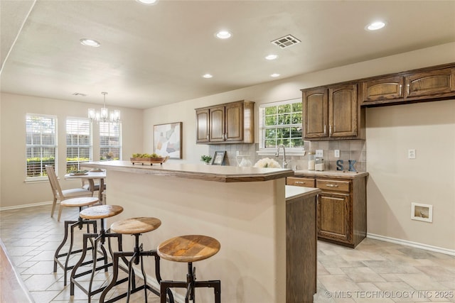 11936 S 98th E Ave, Bixby, OK 74008 - kitchen featuring a kitchen bar, recessed lighting, decorative backsplash, light countertops, and decorative light fixtures
