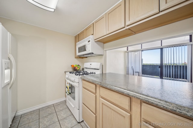 450 W 7th St # 908, Tulsa, OK 74119 - kitchen with white appliances, light brown cabinetry, light tile patterned floors, and dark stone countertops