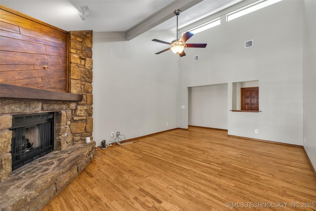 2847 W 115th Pl S, Jenks, OK 74037 - unfurnished living room with ceiling fan, wood finished floors, beamed ceiling, a stone fireplace, and high vaulted ceiling