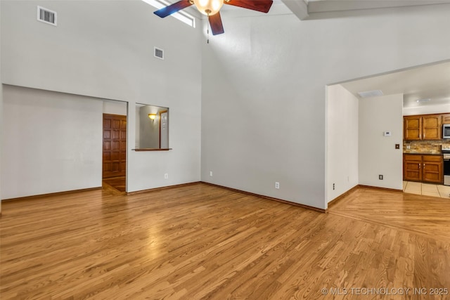 2847 W 115th Pl S, Jenks, OK 74037 - unfurnished living room with ceiling fan, light wood-type flooring, and a towering ceiling